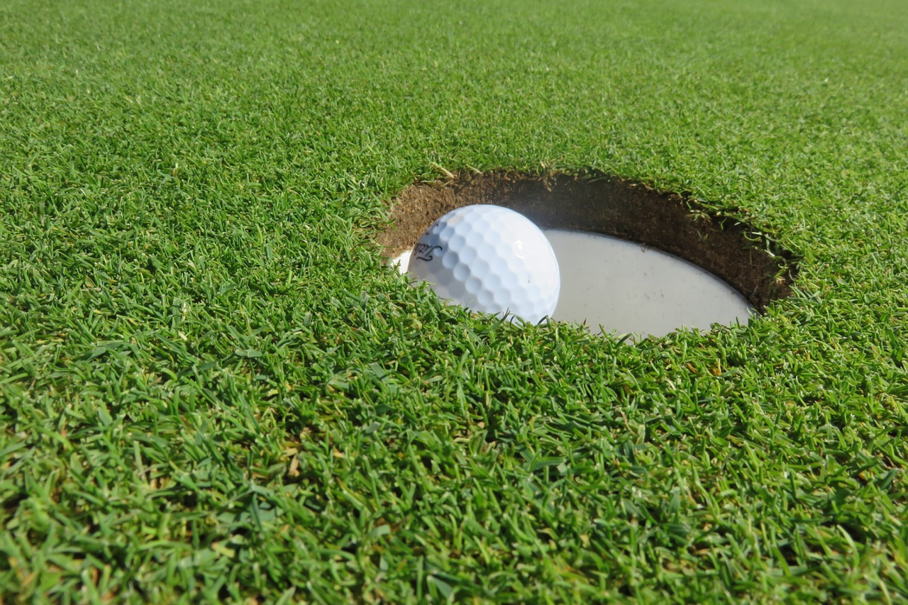 Golf ball falling into a hole.
